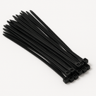Loose bundle of black nylon cable ties fanned diagonally on a plain white studio background