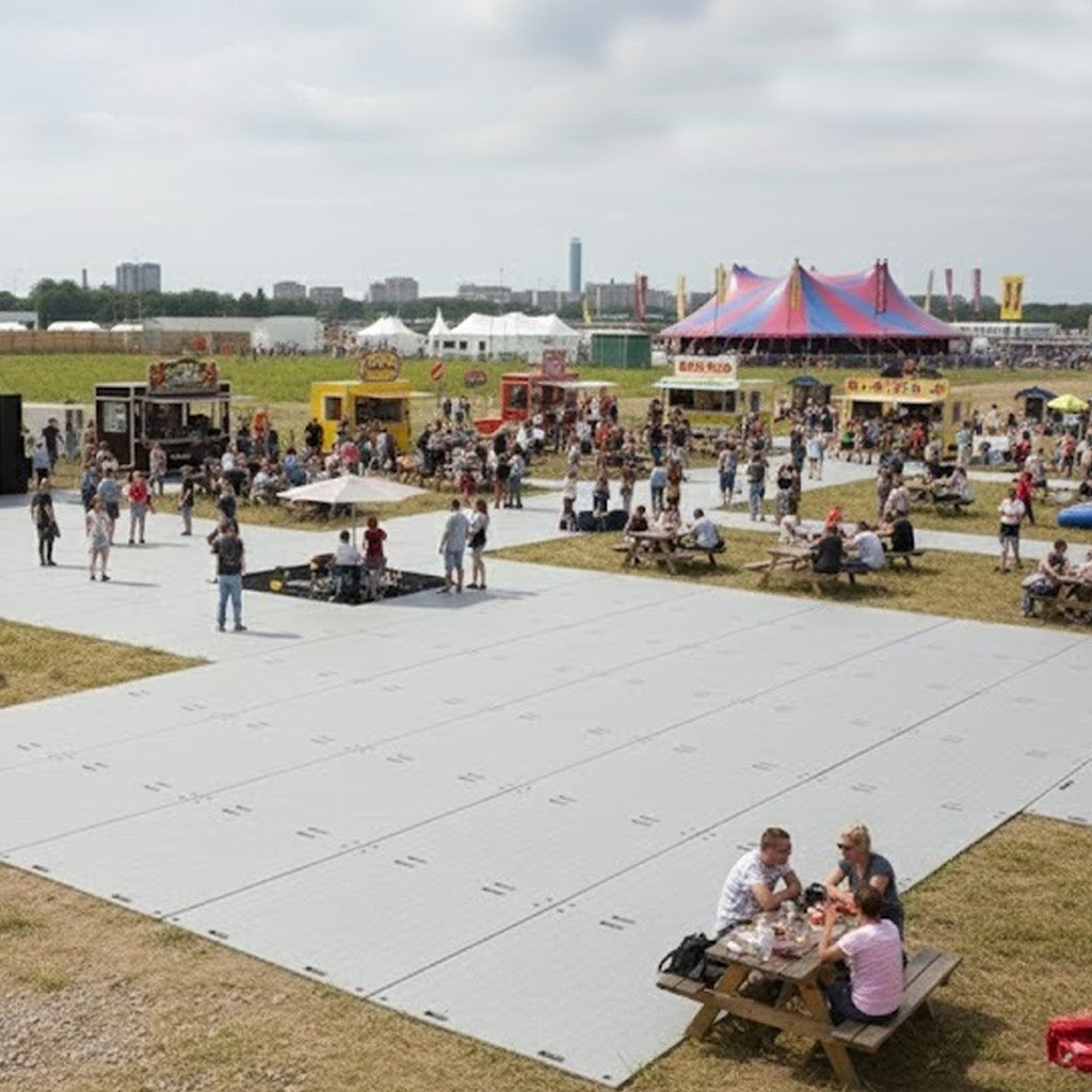 Temporary event flooring made from interlocking ground protection mats, providing stable pedestrian areas for visitors at an outdoor festival or leisure event.