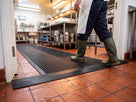Matting edged on all sides forming a flush threshold where it meets quarry tile in a commercial kitchen
