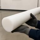 Natural white acetal rod held by gloved hands indoors