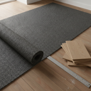 Dark grey rubber crumb acoustic underlay part unrolled over a timber floor beside stacked engineered wood planks