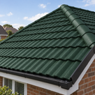 Deep bottle green coated roof tiles on a hipped roof, brick wall and white window frame below