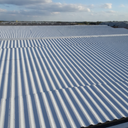 Light grey asbestos roof paint on a corrugated cement warehouse roof in the UK