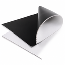 Black fluted sheet curled back over a white one on white, open flute channels along the cut edges