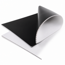 Black fluted sheet curled back over a white one on white, open flute channels along the cut edges