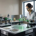 Researcher aligning a green laser across an upright mirror panel on an optical bench in a bright lab