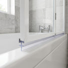 Clear flat-blade seal along the bottom rail of a white bath screen, marble tiling and a tap behind