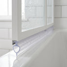 Clear seal with a small teardrop loop under a white bath screen rail, on a white bath
