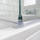 Clear crown-footed seal under the brushed aluminium rail of a bath screen, on a white bath