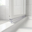 Clear twin-fin seal under a white bifold shower door meeting a white tray, marble tiling behind