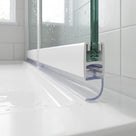 Clear seal with a curling J-hook under a white bath screen rail, on a white bath in a white-tiled room