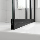 Black seal with a wide angled blade under a black-framed bath screen rail, on a white bath