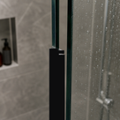 Black bifold seal fitted down the vertical edge of a glass shower panel, tiled niche with a bottle behind