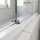Clear 9mm seal pushed between the glass pane and frame on a bifold shower door bottom rail