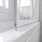 Clear ring-bead seal under the rail of a white-framed folding bath screen, sitting on the bath rim