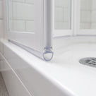 Clear seal with a rounded hollow foot at the base of a white bifold door, on a white tray with chrome waste