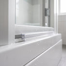 Clear bubble seal pressed into the recess of an aluminium screen rail, droplets on the white bath below