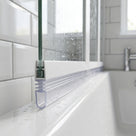 Clear ribbed seal with a hollow U-shaped foot under a white bath screen rail, on a white bath