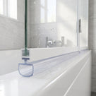 Clear seal with a large D-shaped loop under a bath screen rail on a white bath, wet glass above