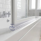 Clear seal with a curled hollow foot under a bath screen rail, metro tiles and bath taps behind