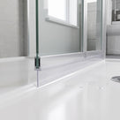 Clear seal running along the foot of a folding shower screen on a white tray beaded with water