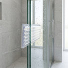 Ribbed clear frame packing strip fitted over a glass panel edge in a shower enclosure, chrome handle behind