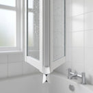 White X-shaped seal at the folded hinge line of a bath screen, wet glass panels and a bath tap behind