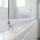 Clear seal with a hollow twin-leg foot under a white bath screen rail, on a white bath