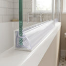 Clear seal pushed between the glass pane and frame on a bifold bath screen bottom rail