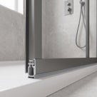 Grey seal fitted under the rail of a grey-framed bifold shower door over a white bath, in situ