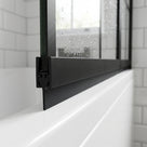 Black seal with a wide blade under a black-framed bath screen rail, on a white bath