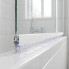 Clear channel seal fitted along the bottom of a folding bifold bath screen, sealing to the bath rim