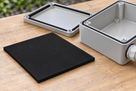 Illustrative black closed-cell silicone sponge sheet beside an enclosure, 200 × 200mm