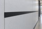 Illustrative 19 x 2.7mm black PVC flat bar installed as a commercial wall cover strip