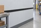 Illustrative 38 x 3mm black PVC flat bar installed as an industrial wall bump strip