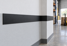 Illustrative black PVC flat bar installed as an industrial wall bump strip