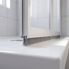 Grey 8mm brush seal sweeping the gap under a bifold shower door bottom rail to the tray