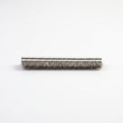 Cut length of brush seal side-on on white, dark-striped white backing above medium grey bristles