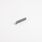 Small cut length of brush seal angled on white, white backing with short upright grey bristles