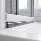 Grey 12mm brush seal sweeping the tall gap under a bifold shower door bottom rail