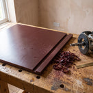 Maroon polyethylene sheet grooved on a timber bench, router to the right and a pile of curled shavings