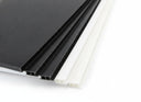 Black and white fluted sheet corners fanned on white, open flute channels visible along the edges