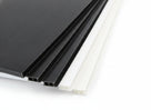 Black and white fluted sheet corners fanned on white, open flute channels visible along the edges