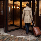 Dark brown carpet insert entrance matting inside the timber revolving door of a boutique hotel, guest stepping in from wet cobbles