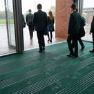 Holly green carpet insert entrance matting across a school entrance on a wet morning, pupils walking in
