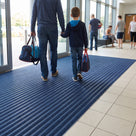 Oxford blue carpet insert entrance matting across a leisure centre entrance lobby, parent and child walking in with swimming bags