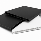 Black and white fluted sheets stacked on white, hollow flutes open along the cut edges