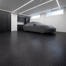 Black recycled coin-pattern PVC matting covering a clean modern private garage floor, a sports car under a dust cover