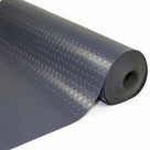 Roll of dark grey coin-pattern PVC floor matting partly unrolled on a white background, showing the round coin studs