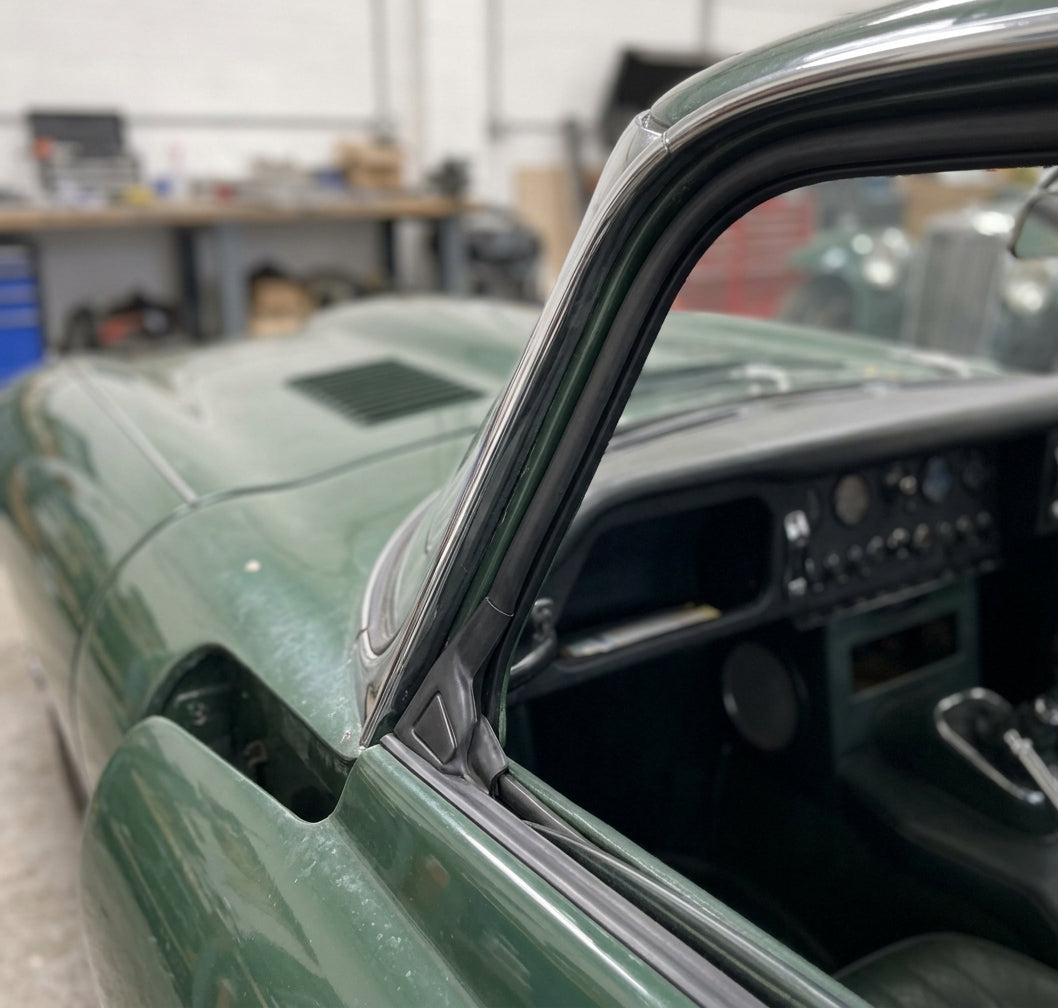 Door seal fitted along the frame of a green classic Jaguar E-Type's windscreen